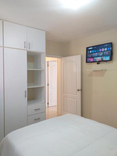 a bedroom with a white bed and a tv on the wall at Urbanization Maratea in Manta