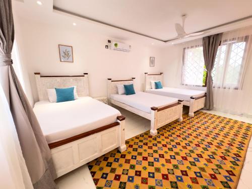 a bedroom with two beds and a rug at Uttoru Creek Villa-2 in Mombasa