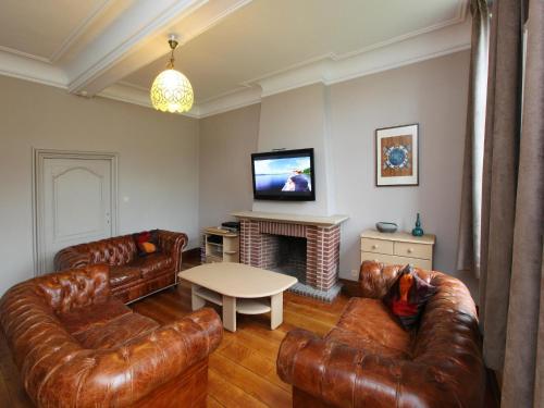a living room with leather couches and a tv at Group Villa with Pool & Sauna in Wanze