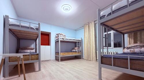 una stanza con tre letti a castello e un tavolo di Zuulun Hostel a Bulgan