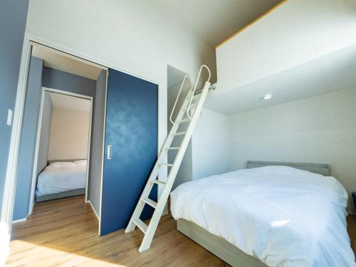a bedroom with a bed with a ladder next to it at torinuma VILLA in Furano