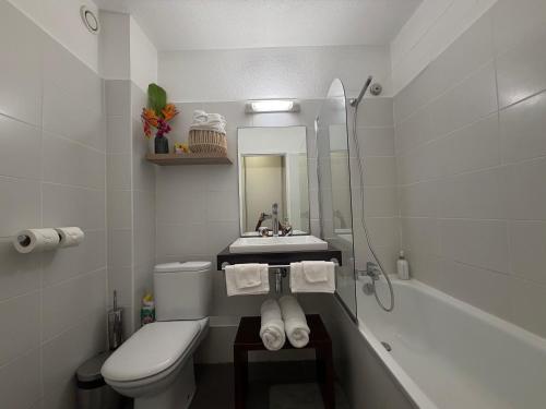 a white bathroom with a sink and a toilet at Studio Les Marines V - calme - vue sur le golf in Saint-François
