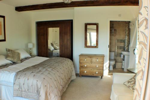 a bedroom with a bed and a dresser and a mirror at Watchcombe House in Colyton