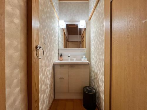a small bathroom with a sink and a mirror at Beachfront Irori in Suo Oshima