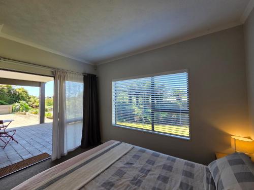 a bedroom with a bed and a large window at Links View Retreat in Omokoroa
