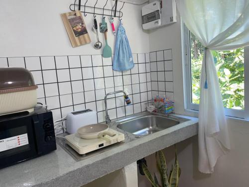 a kitchen counter with a sink and a microwave at Chamin Longbeach Bungalow in Ko Lanta