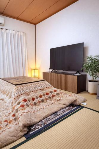 a bedroom with a bed and a flat screen tv at 心斎橋まで7分 なんば1駅 Meeno Home 汐見 一軒家貸切 子ども歓迎 in Osaka