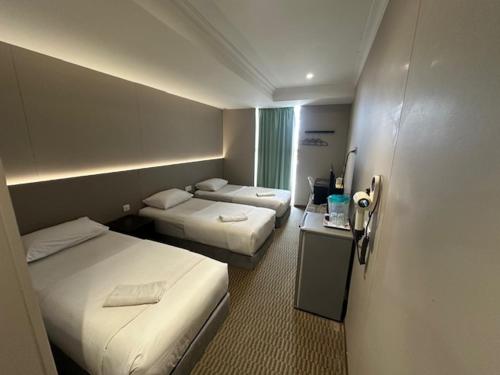 a hotel room with two beds and a table at Li Garden Hotel in Pasir Gudang