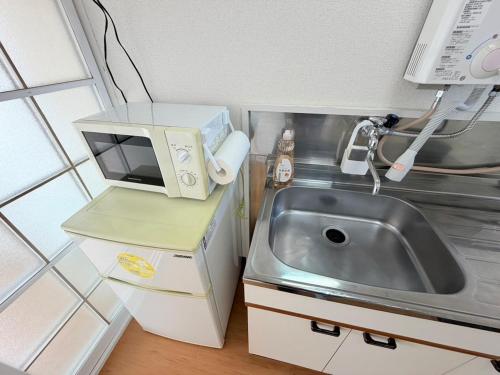a small kitchen with a sink and a microwave at テラスリバーサイド 301 in Miyazaki