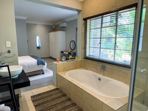 a bathroom with a tub and a bedroom with a bed at Nest - The Homestead in Howick