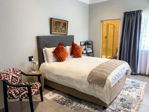 a bedroom with a bed with orange pillows and a chair at Nest - The Homestead in Howick