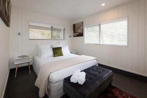 a bedroom with a bed and a stool with a white bedspread at Hahei Island Views in Hahei