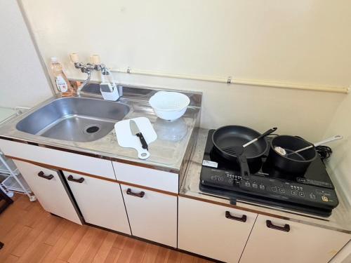 a kitchen with a sink and a stove with pots and pans at パームハウス 202 in Miyazaki