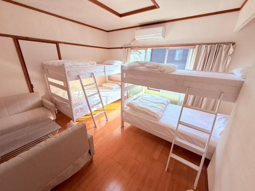 a room with four bunk beds and a couch at パームハウス 202 in Miyazaki
