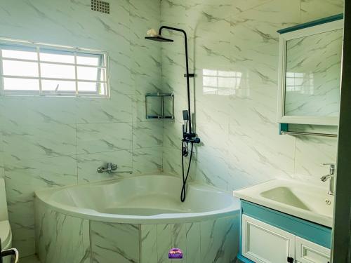 a white bathroom with a tub and a sink at Casuarina Apartments in Livingstone