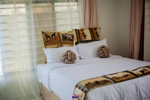 a bedroom with a white bed with two large pillows at Casuarina Apartments in Livingstone