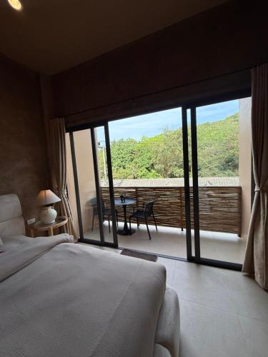 a bedroom with a bed and a balcony with a table at The Petra Boutique Studios in Ko Tao