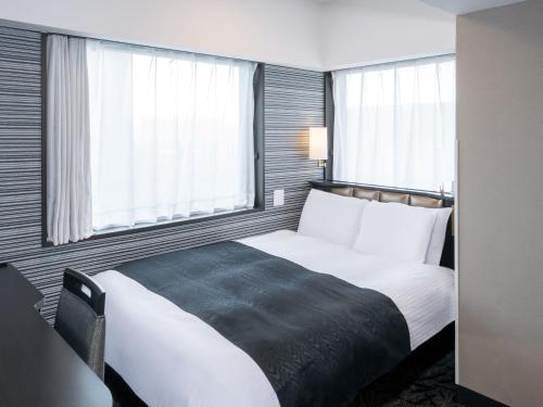 a bedroom with a large white bed with windows at APA Hotel Tokyo Ojima in Tokyo