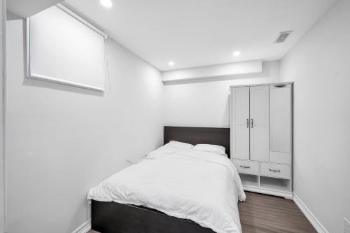 a white bedroom with a bed and a mirror at Newly Renovated 2BR Basement Suite, Private Entry in Pickering