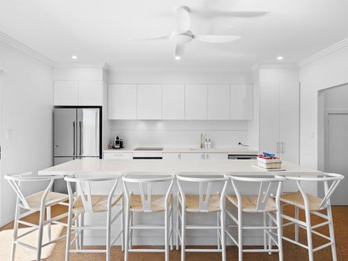 a white kitchen with a white counter and chairs at Exmouth Retreat - 3x3 on the canals in Exmouth