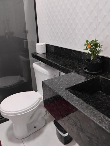 a bathroom with a toilet and a black counter at Mirian nascimento in Camaçari