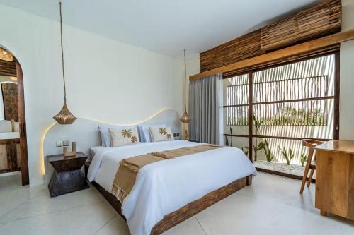 a bedroom with a large bed and a large window at Villa Wedas in Canggu