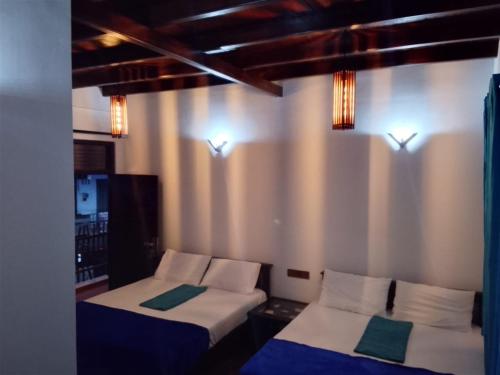 two beds in a room with lights on the wall at Ella Field Side View Rooms & Cafe in Demodera