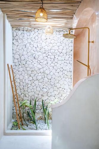 a bathroom with a stone wall with a fish pond at Villa Wedas in Canggu