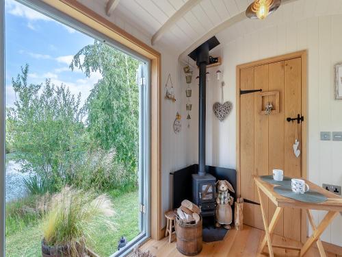 a room with a stove and a large window at Herbie's Shepherd Hut - Uk50229 in Nottingham