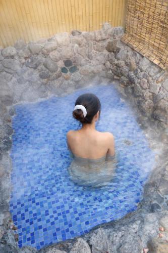 a woman sitting in a pool of water at 新規オープン岩風呂付ゲストハウス織姫 in Fujiyoshida