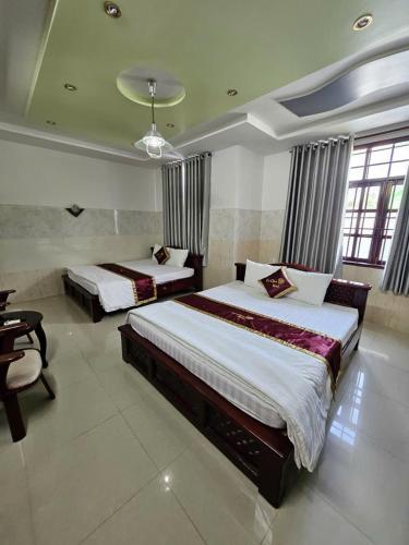 a bedroom with two beds and a table and chairs at Lê Gia HOUSE KG in Kiên Lương