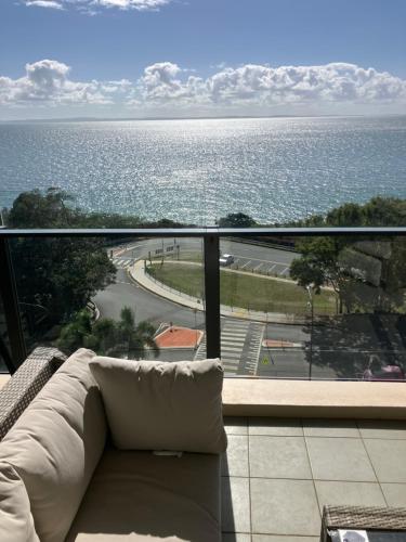 a couch on a balcony with a view of the ocean at Mon Komo Seaview Privately Owned Apartment in Redcliffe