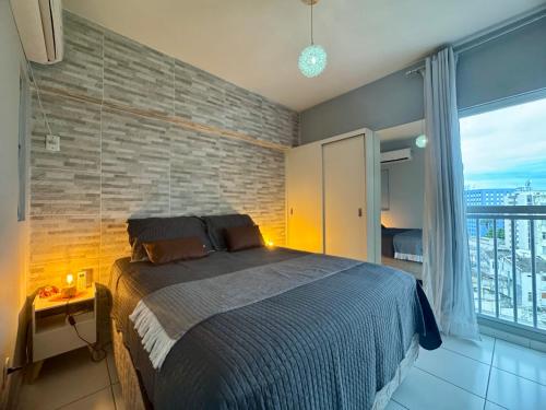 a bedroom with a large bed with a brick wall at Encantos no Porto da Barra in Salvador