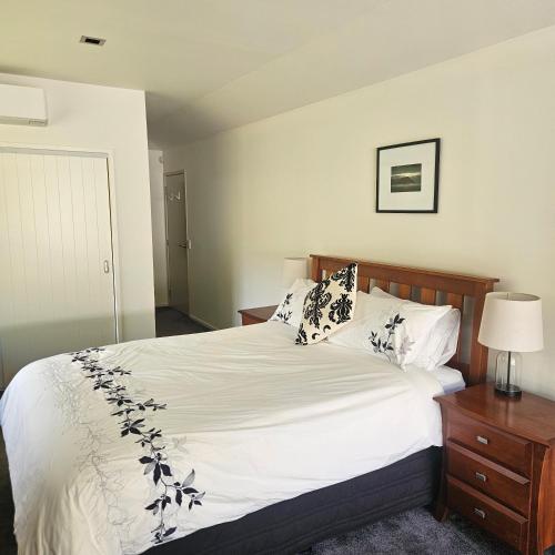 a bedroom with a bed with white sheets and pillows at Seventy-Four on Ramsay in Taupo