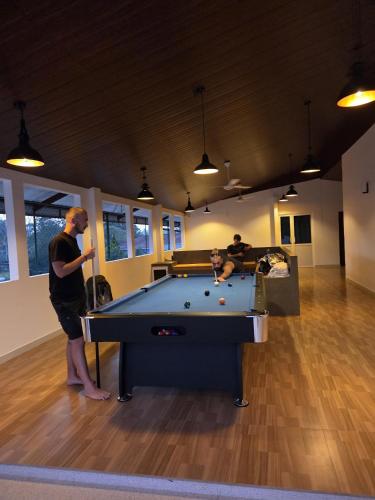 a man standing in a room with a pool table at Ceylon Lodge - Airport Transit Hostel in Negombo