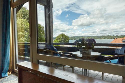 a balcony with a table and a view of the water at Hotel Schloss Berg in Berg am Starnberger See