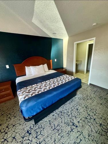 a large bed in a bedroom with a blue wall at Economy Inn in Ada