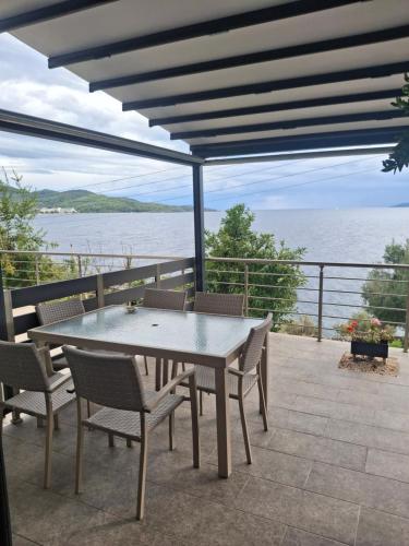 a table and chairs on a patio overlooking the water at Anemos Seaside Apartment in Neos Marmaras