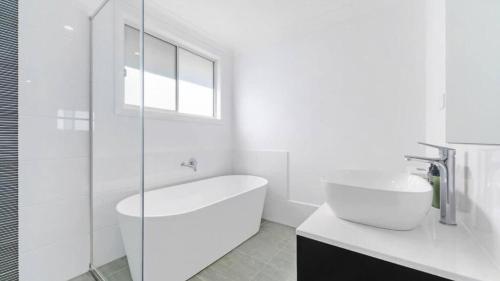 a white bathroom with a tub and a sink at Little Gem in Northwest! in Riverstone