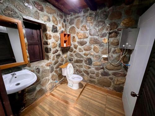 a stone bathroom with a toilet and a sink at บ้านชนเผ่าแคมปิ้งแอนด์รีสอร์ท in Pang Mapha