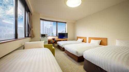 a hotel room with three beds and a window at 太田ナウリゾートホテル in Ota
