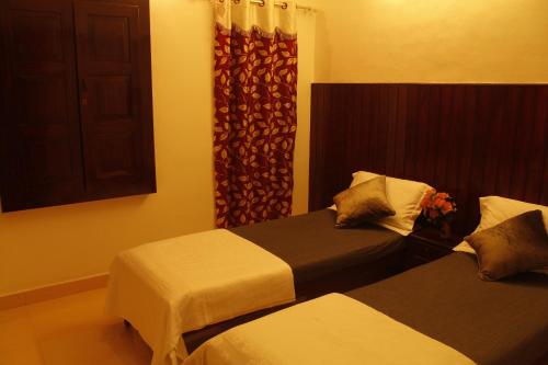 a hotel room with two beds and a window at Neema Homes in Thekkady