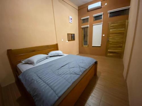 a bedroom with a bed with blue sheets and a window at SumateraTrekingOrangutanPatrol in Bukit Lawang