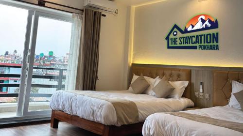 a hotel room with two beds and a window at The Staycation Pokhara in Pokhara