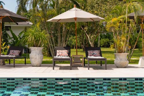 a swimming pool with two chairs and an umbrella and a pool at Moorea Boutique Resort Samui in Ban Tai