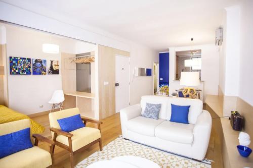 uma sala de estar com um sofá branco e duas cadeiras em Carmo in Chiado Apartment em Lisboa