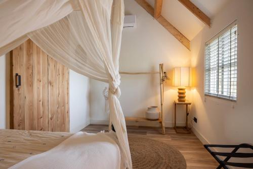 a bedroom with a canopy bed and a window at Somers Loft in Zuid-Beijerland
