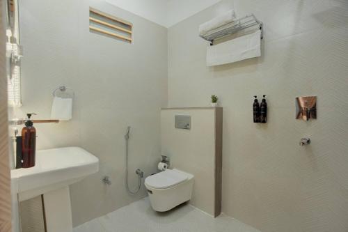 a white bathroom with a toilet and a sink at Sharnam On The Ganges in Rishīkesh