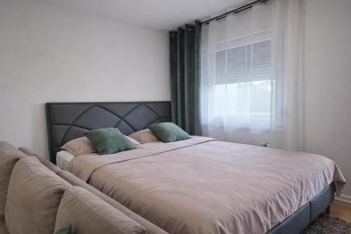 a bedroom with a large bed with a window at Muki Oaza Apartman in Tuzla