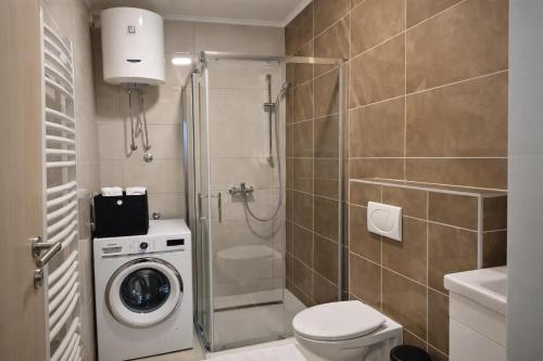 a bathroom with a shower and a washing machine at Hari Apartmani Oaza in Tuzla